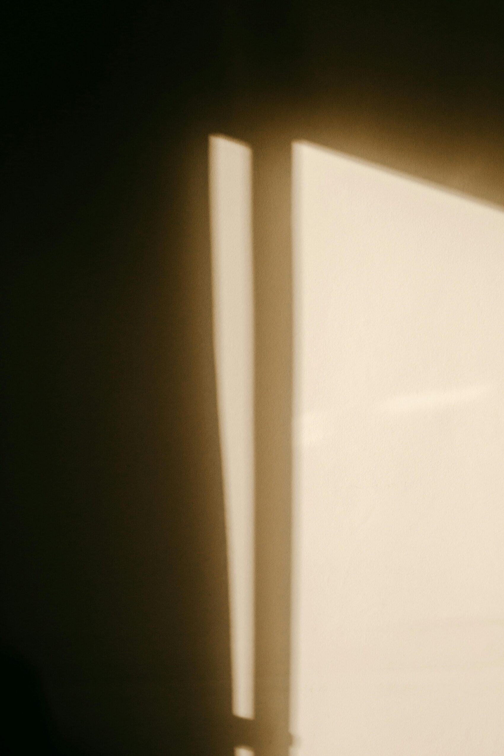 Sonne scheint durch ein Fenster und zeichnet einen Schatten auf die Wand des Raums