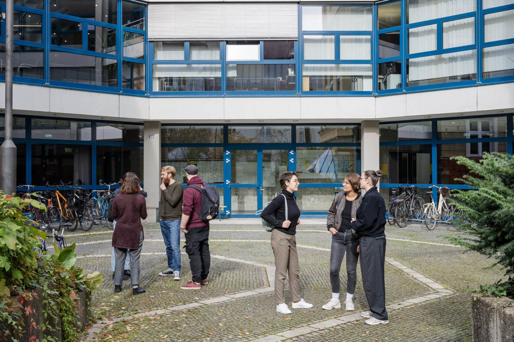 Studierende der HFPH stehen in einer Pause in Grüppchen im Innenhof der Hochschule und unterhalten sich